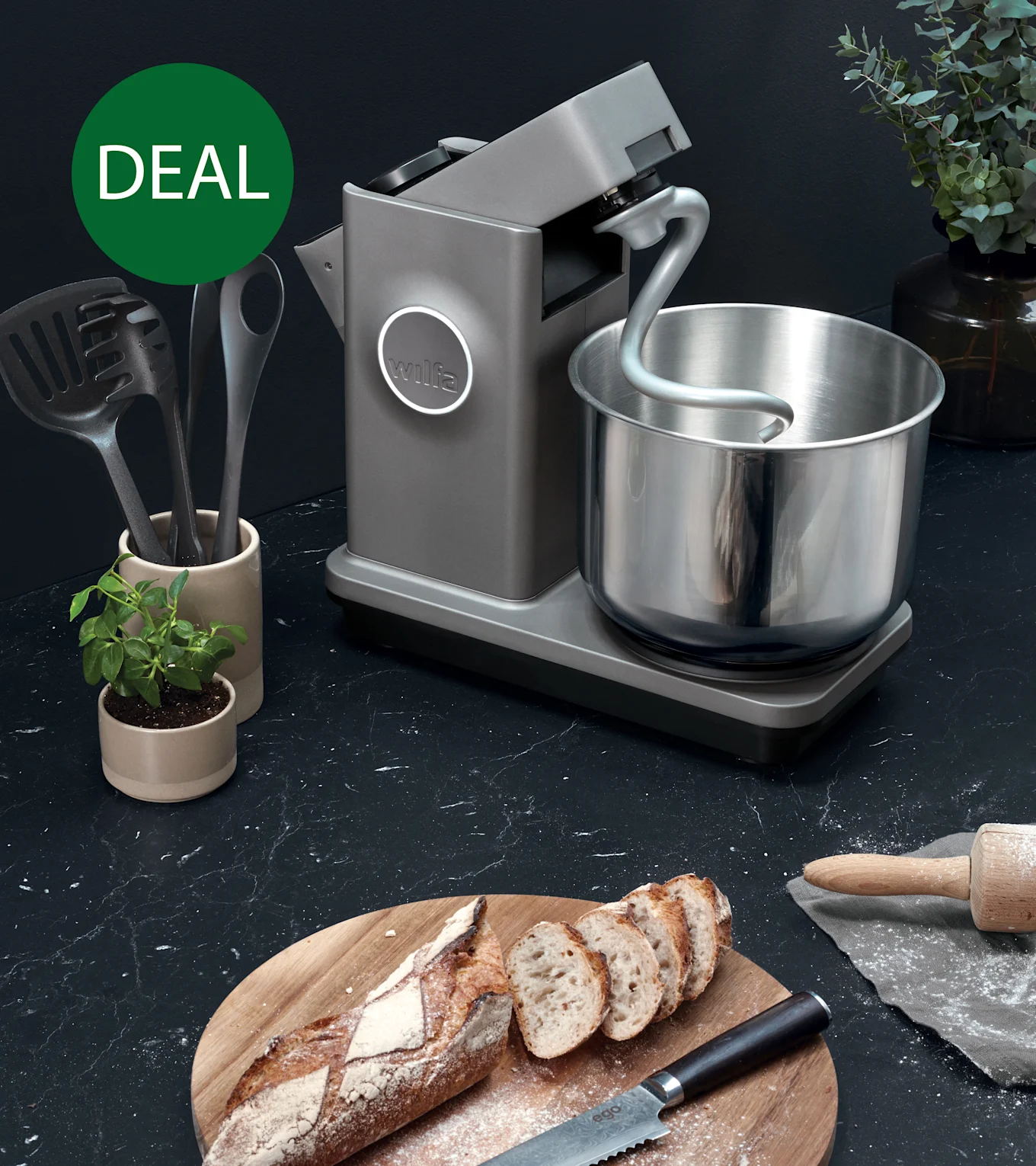 Harmaa yleiskone taikinakoukulla ja teräskulholla tummalla työtasolla viipaloidun leivän kanssa, merkitty vihreällä 'TARJOUS'-ympyrällä.